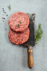 Poster - Raw steak cutlets with old butcher cleaver knife on a light background. top view. copy space for text