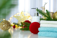 Stack Of Blue And White Towels Folded On The Table, Fir Branches, Christmas Balls And Christmas Lights. SPA Massage Or Beauty Salon, Relaxation And Self Care In Christmas Or New Year Variant.