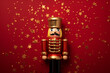 golden nutcracker figurine on a red background with golden stars confetti flat lay