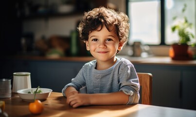 Portrait of a little boy sitting at the table in the kitchen