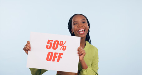 Wall Mural - Portrait, sale and poster with a retail black woman in studio on blue background for promo discount. Smile, shopping and savings with a happy young commercial employee holding a sign for information