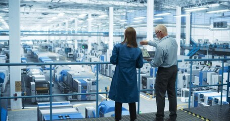 Leinwandbilder - Male and Female Engineers Standing with Their Back to Camera, Using Laptop Computer and Talking in a Factory Facility with Equipment Producing Modern Electronic Components for Different Industries