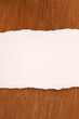Wooden background and blank piece of light colored torn paper for text.