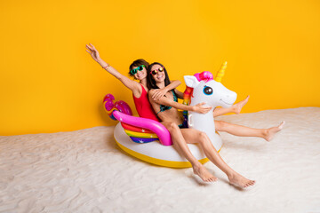 Wall Mural - Photo of positive girl tourist enjoy summer time ride on inflatable rubber unicorn buoy isolated over bright color background