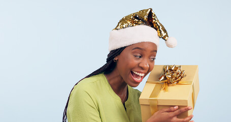 Poster - Excited black woman, box and Christmas surprise for gift, present or prize against a studio background. Face of happy and surprised African female person holding ribbon package, parcel or gifts