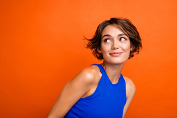 Wall Mural - Photo of cute dreamy lady wear blue singlet smiling looking empty space isolated orange color background