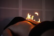 © Alex Vog - FIre massage alternative therapy. Wellness rehabilitation for patient in medical clinic office. Fire flame on man back in dark room, close up. Rehab relaxing massage concept. Copy ad text space