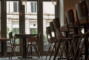 Wall Mural - Beautiful design inside of Restaurant. Decorated with wooden table with chairs next to glass doors. Space for text, Selective focus.