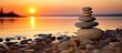 Sunset beach with balanced rock pyramid on sea pebbles Golden sea bokeh in background Zen stones meditation spa harmony
