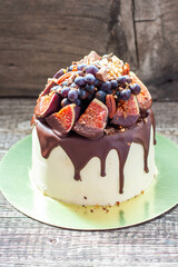 Wall Mural - Delicious cake with figs dipped into melted chocolate, pecan nuts, grapes, chocolate bites and cookies on the top. Concept of autumn or summer cake