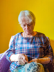 Senior woman sews, wrinkled hands of the old seamstress.elderly woman.