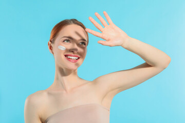 Wall Mural - Beautiful young woman shading herself with hand from sunlight on light blue background