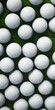 A bunch of golf balls sitting on top of a lush green field. Suitable for sports and leisure themes