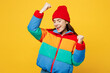 Young overjoyed woman she wears padded windbreaker jacket red hat casual clothes doing winner gesture celebrate clenching fists isolated on plain yellow background studio portrait. Lifestyle concept.