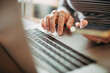 © Marko Geber - Close-up of a persons hands typing on a laptop keyboard