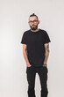 © satura_ - Portrait of attractive handsome man millennial with beard who looks into camera on isolated simple background and wears black t-shirt from premium organic materials