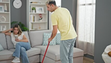 Wall Mural - Beautiful couple cleaning while girlfriend using smartphone at home