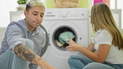 Wall Mural - Beautiful couple smiling confident washing clothes at laundry room