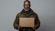 © Davidtarias - African american man in green jacket holding laptop isolated on grey