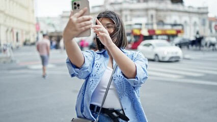 Wall Mural - Young beautiful hispanic woman taking selfie with smartphone in the streets of Vienna