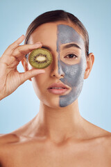 Wall Mural - Portrait, kiwi and mask for skincare with a woman in studio on a blue background for antiaging beauty. Face, facial and fruit with an attractive young female holding a berry for organic treatment