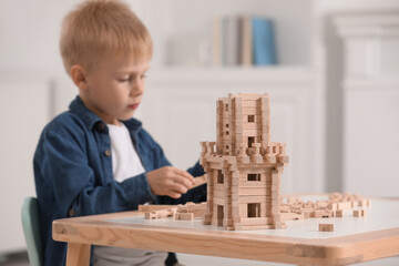 Canvas Print - Cute little boy playing with wooden tower at table indoors, selective focus. Child's toy