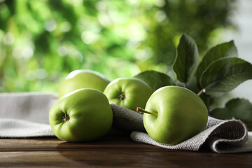 Fresh ripe green apples and leaves on wooden table outdoors