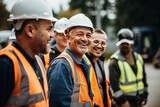 Fototapeta  - Men builders in reflective vests and helmets pose for photo smiling during work break. Cheerful workers friends in warm uniforms stand on construction site.
