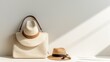 © พงศ์พล วันดี - A summer accessory set with a white woven handbag and a straw fedora hat on a white background. The handbag has a brown leather handle and a flap closure. The hat has a black ribbon around the base