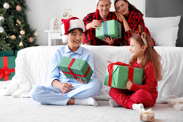 Canvas Print - Little children with Christmas presents and their parents in bedroom