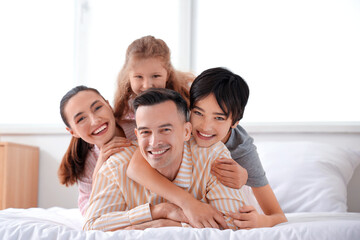 Canvas Print - Little children with their parents hugging in bedroom