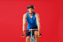 Young Man Riding Bicycle On Red Background, Front View