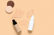 Bottles of makeup foundation with sponges and samples on beige background