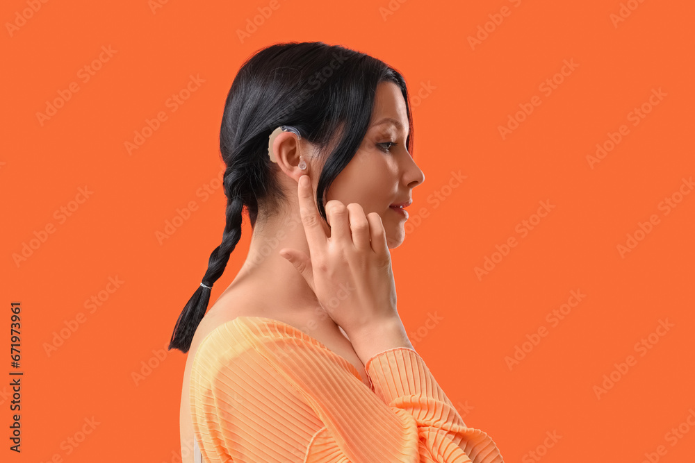 Young woman with hearing aid on red background, closeup