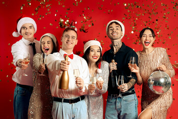 Sticker - Group of friends with champagne and falling confetti on red background. New Year celebration