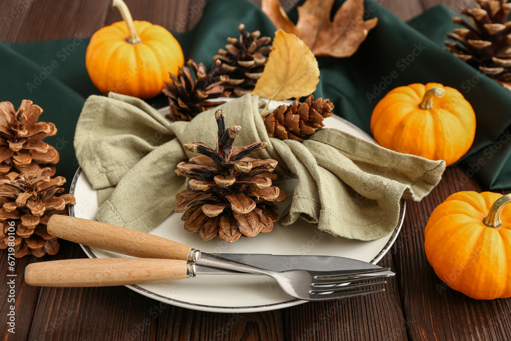Autumn table setting with pumpkins, cones and dried leaves on wooden background