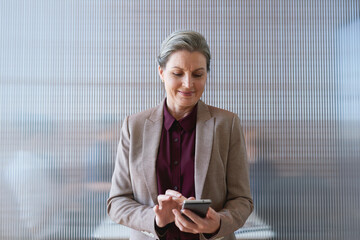 Poster - Phone, business woman and typing in office, social media or internet browsing online. Technology, cellphone and happy senior female ceo with mobile smartphone for networking, texting or web scrolling