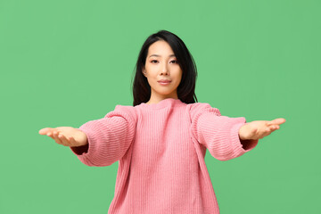 Poster - Young Asian woman opening arms for hug on green background