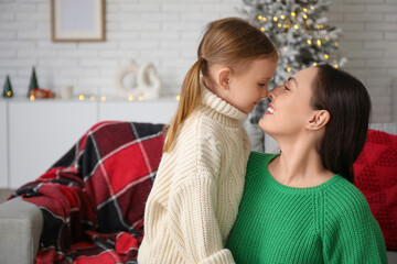 Young mother with her little daughter touching noses at home on Christmas eve