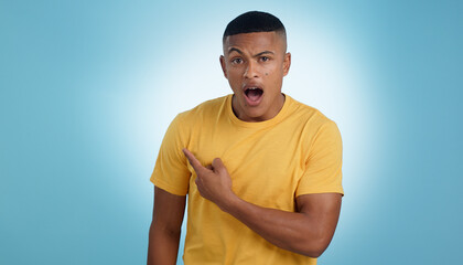 Canvas Print - Pointing, shock and portrait of man in a studio with mockup for marketing, advertising or promotion. Surprise, wow and young male person with a show hand gesture isolated by blue background.