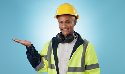 Canvas Print - Happy, construction worker and portrait with hand advertising, promotion or mockup in blue background. Happy, face and builder show safety announcement, presentation or branding space in studio