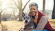 Portrait of senior african american woman playfully holding her dog in park. Love for animals concept.
