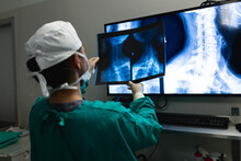 Asian Female Surgeon Looking At X-ray Scans On Screen In Operating Theatre At Hospital