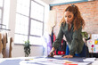 © Wavebreak Media - Focused biracial female fashion designer cutting fabric with scissors in sunny studio