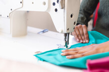 Biracial Female Fashion Designer Using Sewing Machine In Sunny Studio