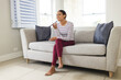 © Wavebreak Media - Happy biracial woman sitting on couch and talking on smartphone at home