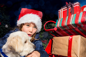 Wall Mural - Pretty little girl impatiently waiting to open presents near the Christmas tree