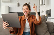 © Mix and Match Studio - Excited cute woman winning, celebrating, looking at digital tablet and rejoicing, triumphing, reading great news, sitting on couch at home