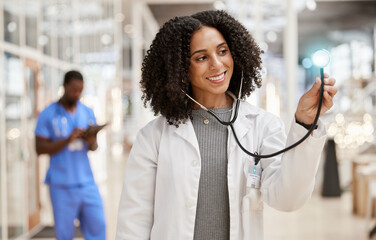 Canvas Print - Woman, doctor and stethoscope with thinking, hospital and smile for check, overlay and light in corridor. African medic, tools and happy for healthcare job, service and listening with glow in clinic