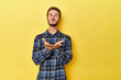 © Asier - Young Caucasian man on a yellow studio background folding lips and holding palms to send air kiss.
